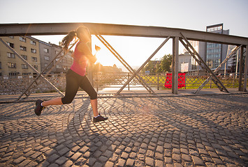 Image showing woman jogging across the bridge at sunny morning
