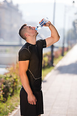 Image showing man drinking water from a bottle after jogging