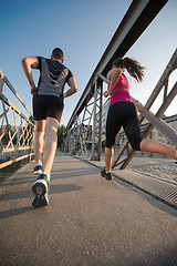 Image showing young couple jogging across the bridge in the city