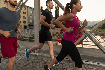 Image showing group of young people jogging across the bridge