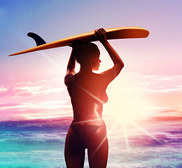 Image showing silhouette of surfer with surfboard at sunrise