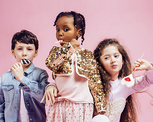 Image showing lifestyle people concept: diverse nation children playing together, caucasian boy with african little girl holding candy happy smiling 