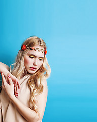 Image showing young pretty blond girl with curly blond hair and little flowers happy smiling on blue sky background, lifestyle people concept 