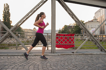 Image showing woman jogging across the bridge at sunny morning