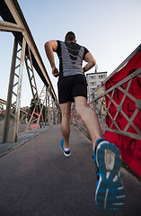 Image showing man jogging across the bridge at sunny morning