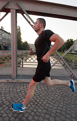 Image showing man jogging across the bridge at sunny morning