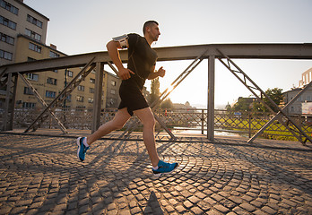 Image showing man jogging across the bridge at sunny morning