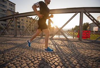 Image showing man jogging across the bridge at sunny morning