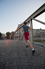 Image showing man jogging across the bridge at sunny morning