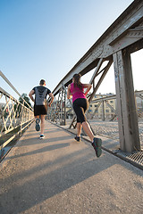 Image showing young couple jogging across the bridge in the city