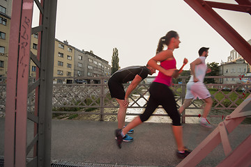 Image showing group of young people jogging across the bridge