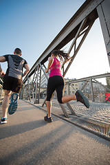 Image showing young couple jogging across the bridge in the city