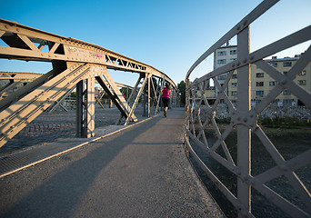 Image showing woman jogging across the bridge at sunny morning