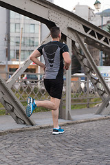 Image showing man jogging across the bridge at sunny morning