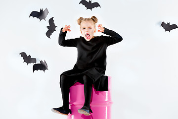 Image showing Little girl witch in black dress over magical accessories. Halloween, the studio evening.