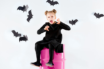 Image showing Little girl witch in black dress over magical accessories. Halloween, the studio evening.