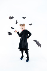 Image showing Little girl witch in black dress over magical accessories. Halloween, the studio evening.