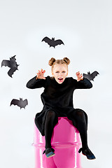 Image showing Little girl witch in black dress over magical accessories. Halloween, the studio evening.