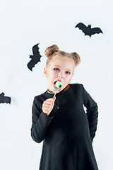 Image showing Little girl witch in black dress over magical accessories. Halloween, the studio evening.