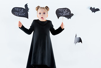 Image showing Little girl witch in black dress over magical accessories. Halloween, the studio evening.