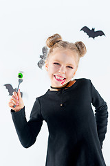 Image showing Little girl witch in black dress over magical accessories. Halloween, the studio evening.