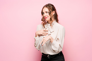 Image showing The serious frustrated young beautiful business woman on pink background