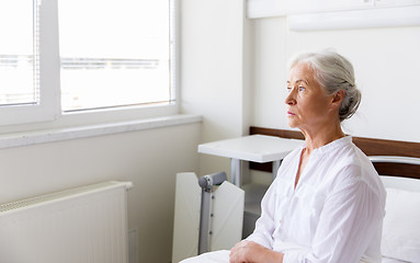 Image showing sad senior woman sitting on bed at hospital ward