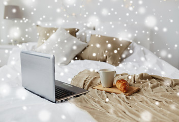 Image showing laptop, coffee and croissant on bed at cozy home