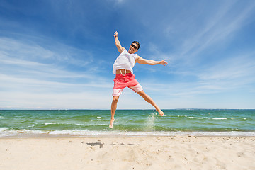 Image showing smiling young man jumping on summer beach