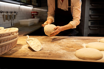 Image showing baker portioning dough with bench cutter at bakery