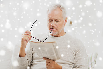 Image showing senior man in glasses reading newspaper at home