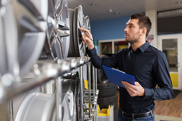 Image showing auto business owner and wheel rims at car service