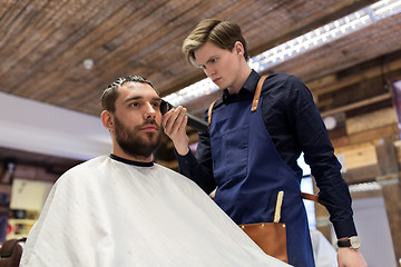 Image showing man and barber with trimmer cutting hair at salon