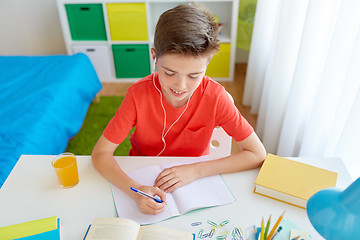 Image showing happy student boy writing to notebook at home