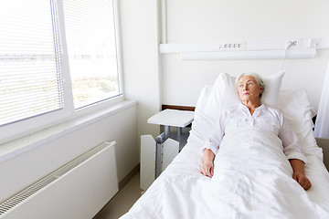 Image showing sad senior woman lying on bed at hospital ward