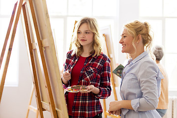 Image showing artists discussing painting on easel at art school