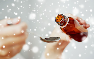 Image showing woman pouring medication from bottle to spoon