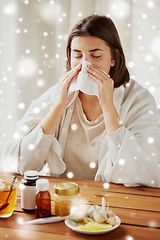 Image showing sick woman with medicine blowing nose to wipe