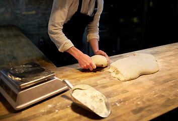 Image showing baker portioning dough with bench cutter at bakery