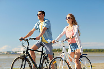 Image showing happy young couple riding bicycles at seaside