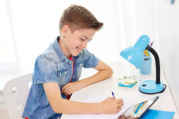 Image showing happy student boy writing to notebook at home