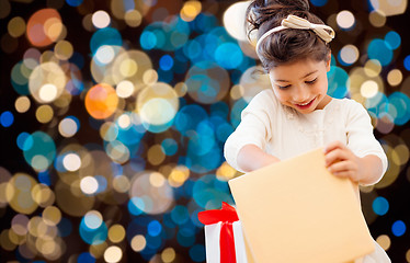 Image showing smiling little girl with gift box over lights
