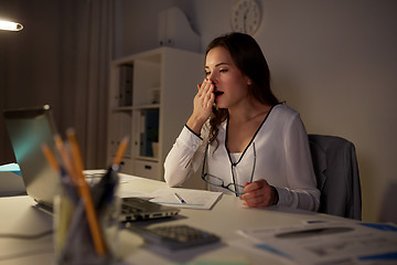 Image showing tired woman with papers yawning at night office