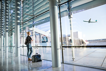 Image showing Young woman waiting at airport, looking through the gate window.