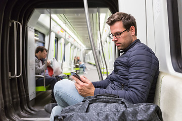 Image showing Male commuter reading from mobile phone screen in metro.