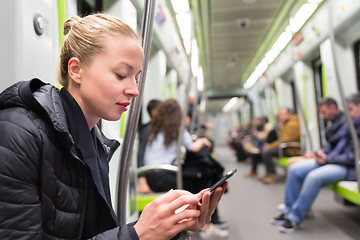 Image showing Young girl reading from mobile phone screen in metro.