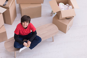 Image showing boy sitting on the table with cardboard boxes around him top vie