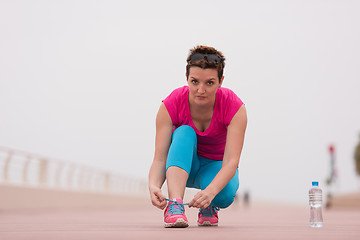 Image showing Young woman tying shoelaces on sneakers