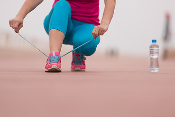 Image showing Young woman tying shoelaces on sneakers