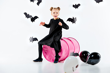 Image showing Little girl witch in black dress over magical accessories. Halloween, the studio evening.